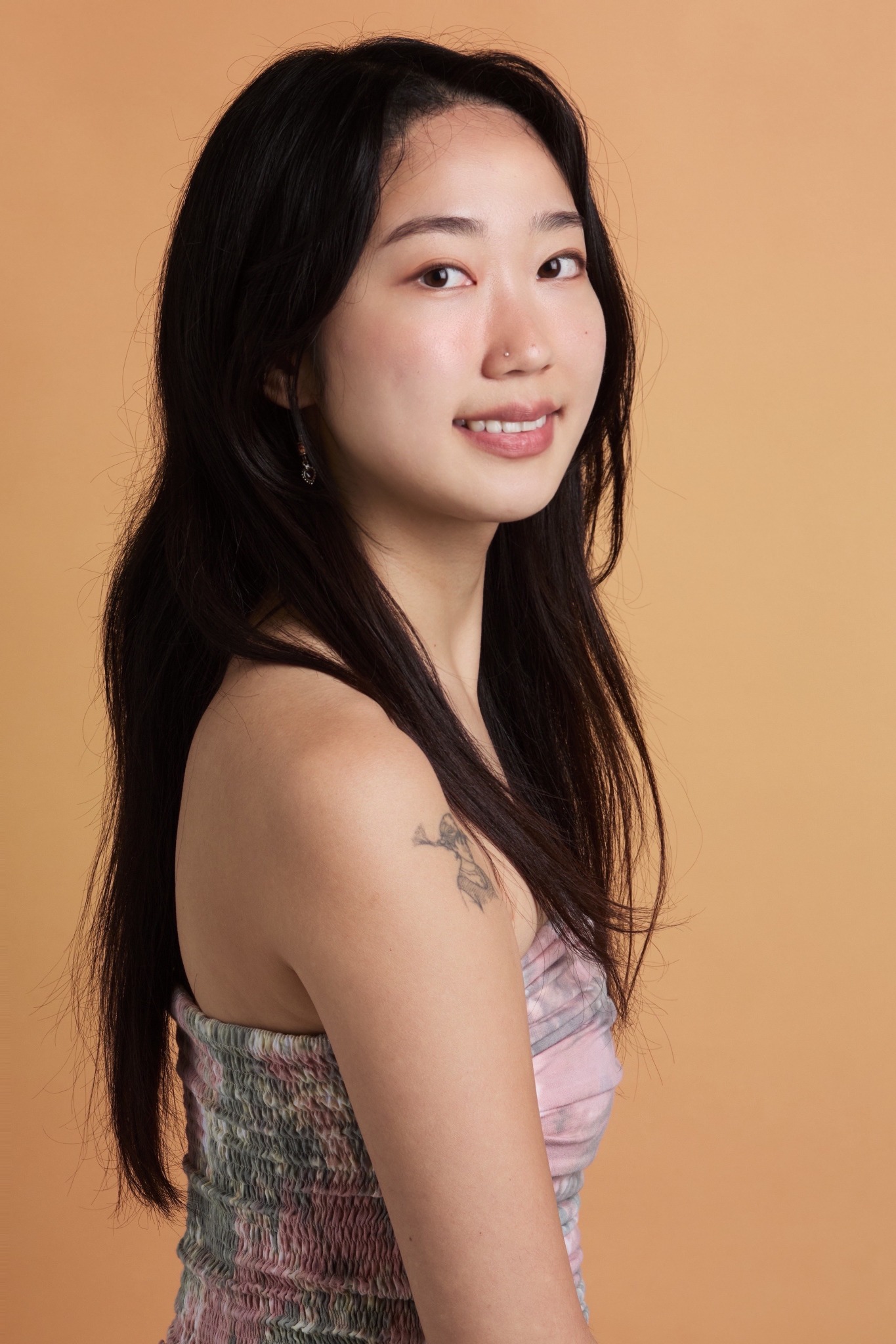 Portrait of Jiyoo Kim against a warm terracotta background